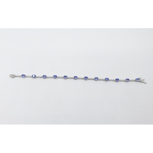 181 - A Tanzanite and Diamond line Bracelet claw-set twelve oval-cut tanzanite with rows of six pavé-set b... 