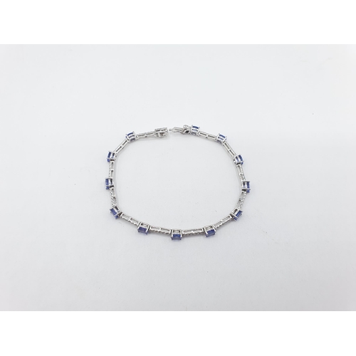 181 - A Tanzanite and Diamond line Bracelet claw-set twelve oval-cut tanzanite with rows of six pavé-set b... 