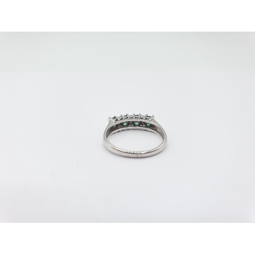 202 - A Diamond and Emerald Ring channel and pavé-set alternating pairs of step-cut emeralds and eight-cut... 