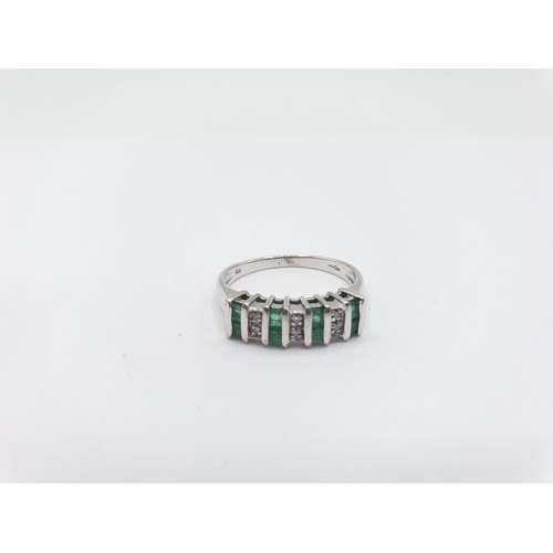 202 - A Diamond and Emerald Ring channel and pavé-set alternating pairs of step-cut emeralds and eight-cut... 