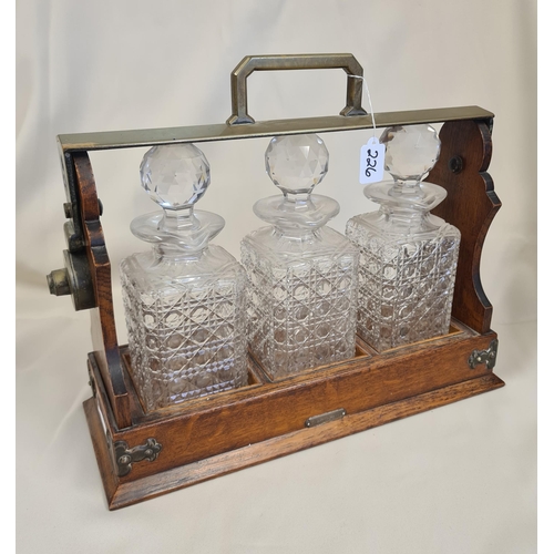 226 - A brass bound oak Tantalus with three cut glass decanters and stoppers