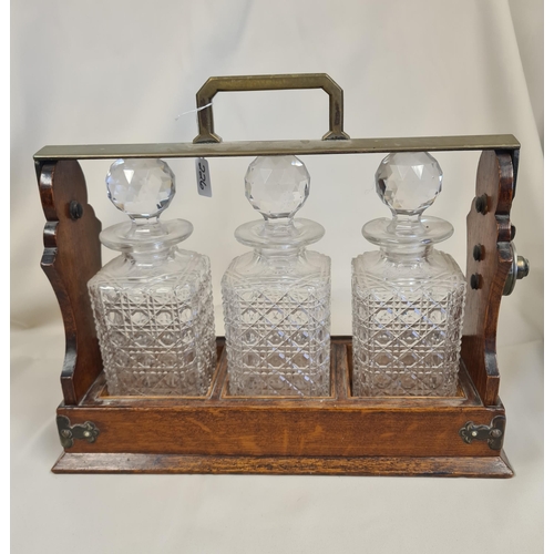 226 - A brass bound oak Tantalus with three cut glass decanters and stoppers