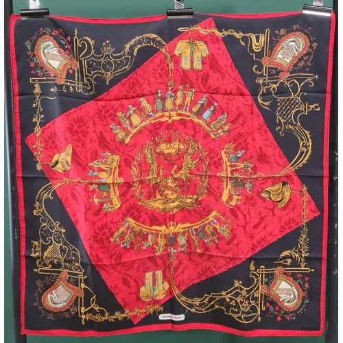 243 - A vintage Hermes silk Scarf; 'Alsace' figures around a crest in red and gold on black, approx 83cm x... 