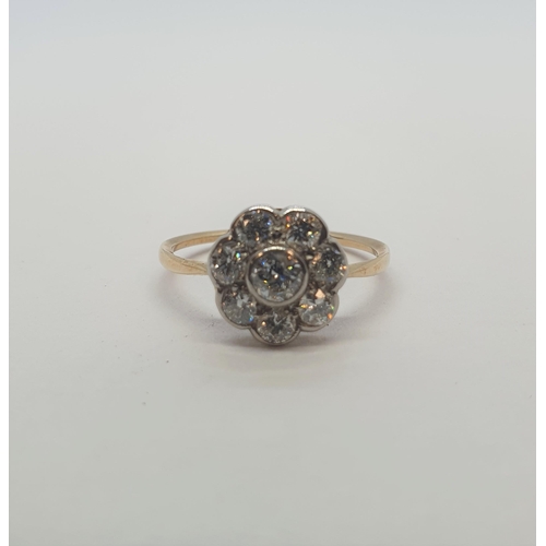 186 - A Diamond flower Cluster Ring rubover-set old-cut stone within a frame of seven smaller stones, unma... 