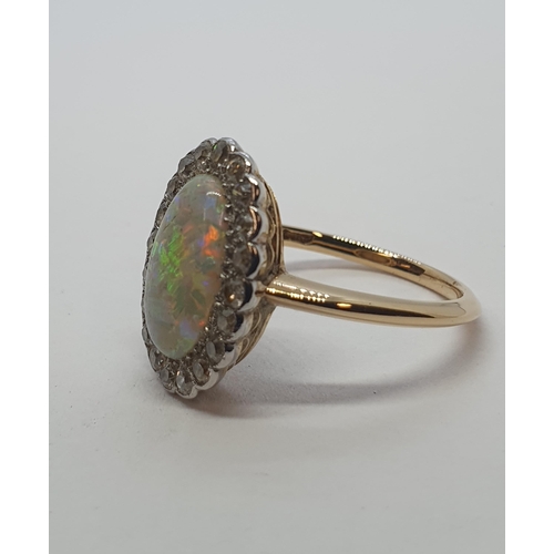 187 - An Opal and Diamond Cluster Ring set oval opal cabochon (cracked) within a frame of eight-cut diamon... 