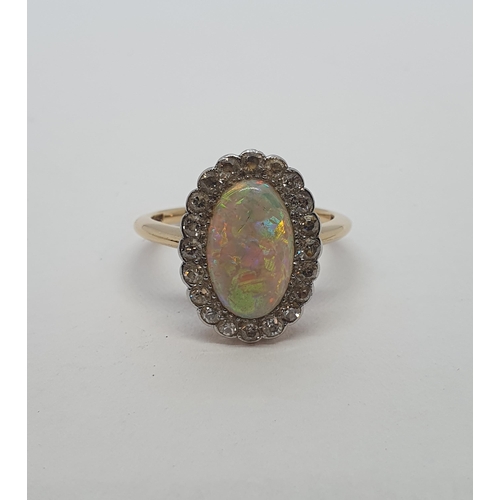 187 - An Opal and Diamond Cluster Ring set oval opal cabochon (cracked) within a frame of eight-cut diamon... 