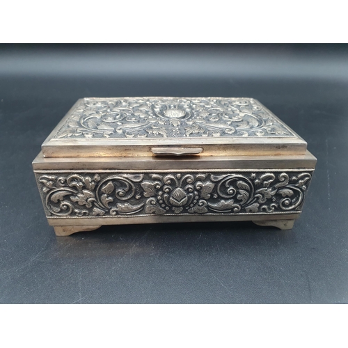 121 - A Continental silver Cigarette Box with leafage scroll embossing and chasing, on bracket feet, 5in, ... 