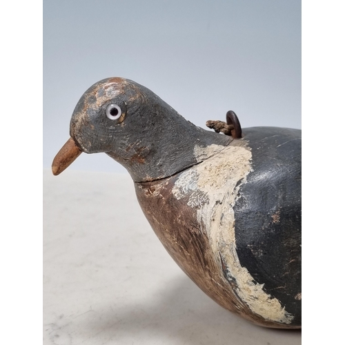 19 - A carved and painted English Pigeon Decoy with inset glass eyes and rig eyelets, with associated woo... 