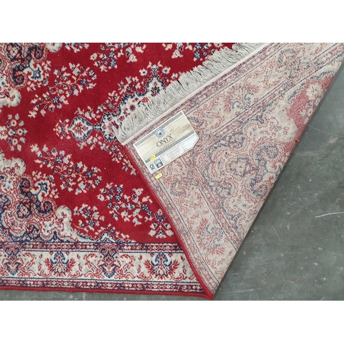 55 - A Persian style Rug with floral and scrolled design on a red ground, 5ft 5in x 3ft 11in