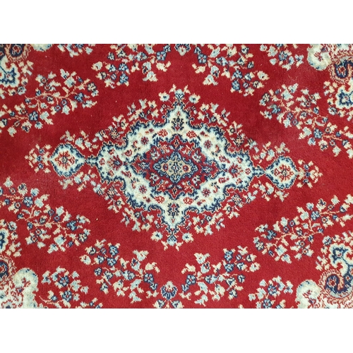 55 - A Persian style Rug with floral and scrolled design on a red ground, 5ft 5in x 3ft 11in