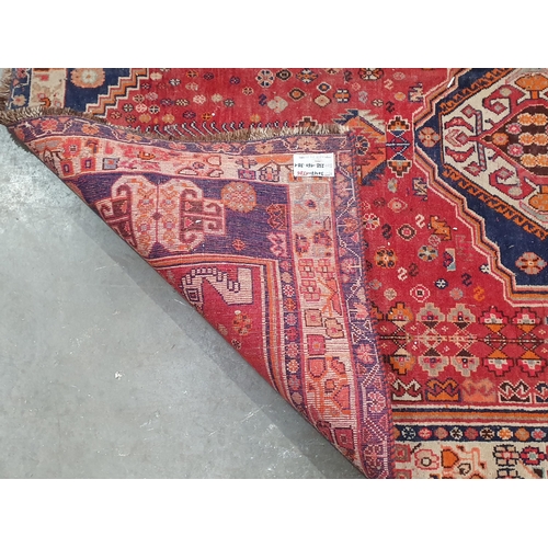 65 - A Persian rug with stylised motifs to the borders and central lozenge on a red ground, A/F 7ft 8in x... 