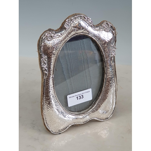 133 - An Edward VII silver Photograph Frame with hammered and floral embossed design, oval aperture, Birmi... 