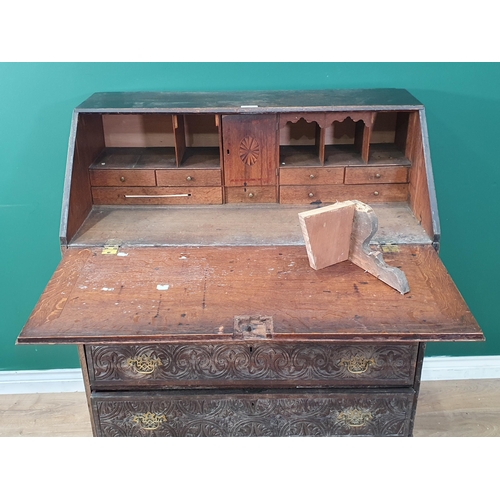 454 - A carved oak Bureau with fall front enclosing pigeonhole and drawer interior above four long graduat... 