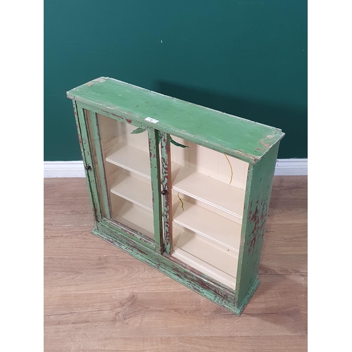 47 - A green and cream painted Cupboard with moulded cornice above pair of glazed sliding doors, 2ft 4