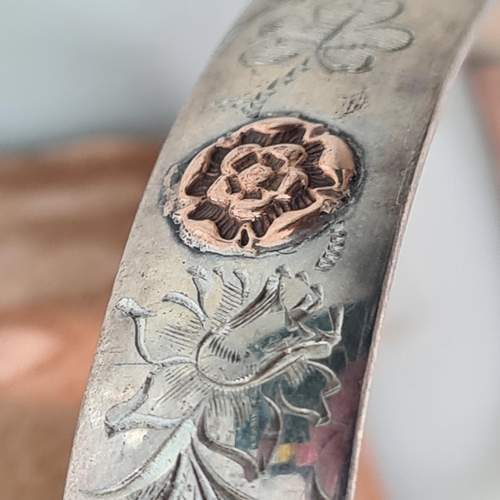 91 - An Elizabeth II silver Slave Bangle with thistle engraving and gold rosettes, Birmingham 1978