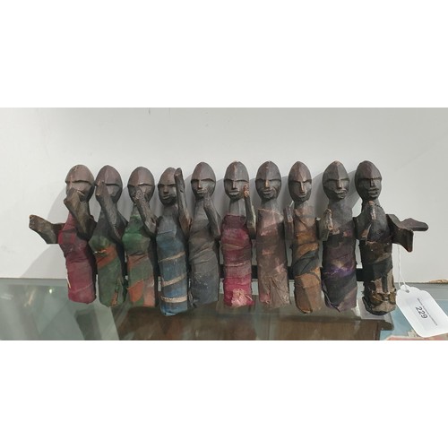 229 - A child's African carved Toy in the form of a row of figures with moving arms and cloth covered bodi... 