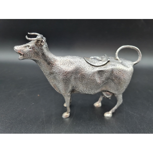 142 - A white metal Cow Creamer with hinged cover having bee finial, 6in