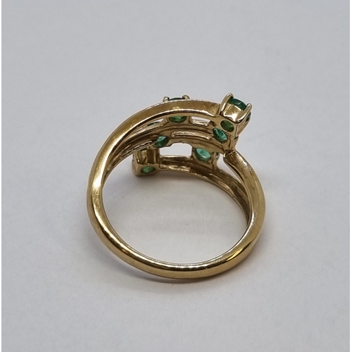 171 - An Emerald Ring peg-set six round emeralds in a cross-over setting in 9ct gold, ring size J 1/2, app... 