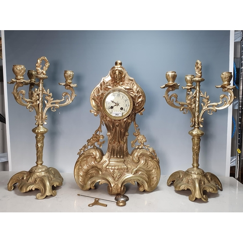 262 - A brass large three piece Clock Garniture with mask surmount above the circular dial and with design... 