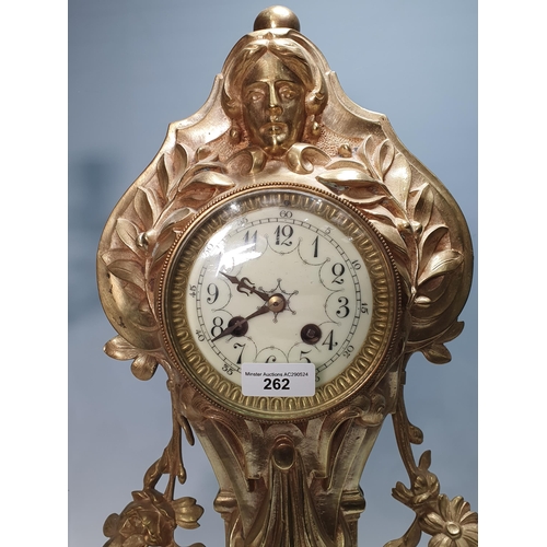 262 - A brass large three piece Clock Garniture with mask surmount above the circular dial and with design... 