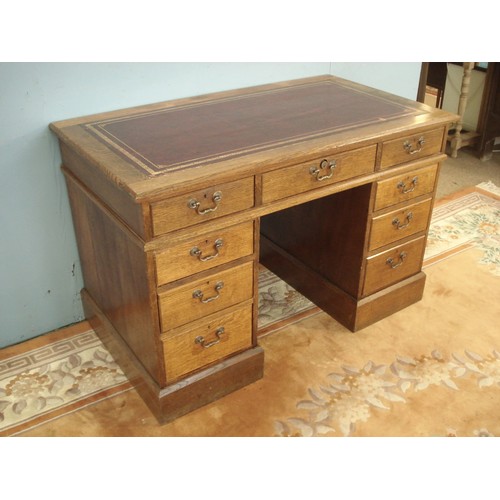 52 - An Edwardian oak Pedestal Writing Desk with tolled leather inset writing surface above nine drawers ... 