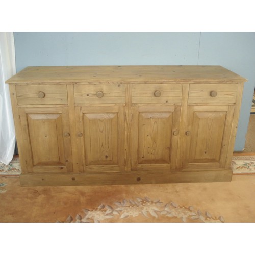 19 - A stripped pine enclosed Dresser Base fitted four frieze drawers above four panelled cupboard doors ... 