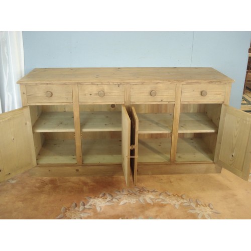 19 - A stripped pine enclosed Dresser Base fitted four frieze drawers above four panelled cupboard doors ... 
