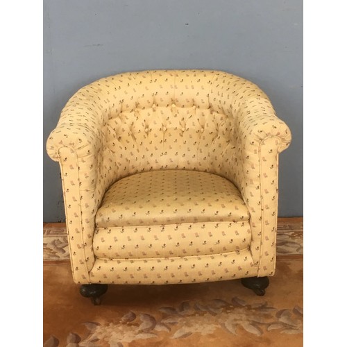 63 - A yellow floral button upholstered Tub Chair on bun feet and casters 2ft 3in W x 2ft 7in H x 2ft 6in... 