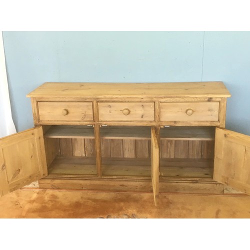 69 - An antique pine Dresser Base fitted three frieze drawers above three panelled cupboard doors on plin... 