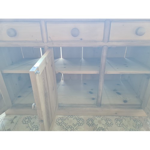 36 - A pine Dresser Base fitted three frieze drawers above three cupboard doors with applied moulding rai... 