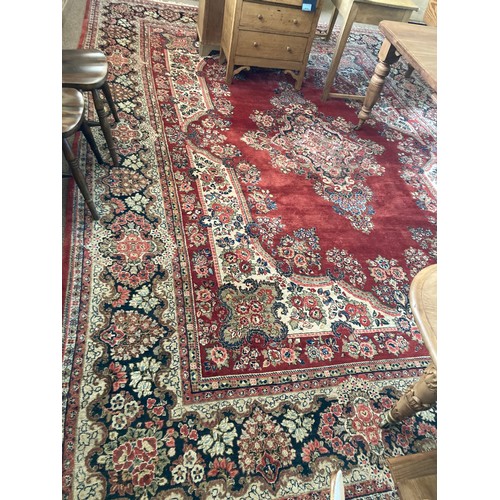 105 - A large woollen Persian style Carpet with floral design on red ground within cream border A/F 15ft L... 
