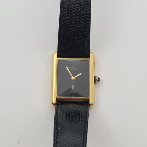 129 - A lady's Must de Cartier manual wind Tank Wristwatch the rectangular black dial with gold hands, sap... 