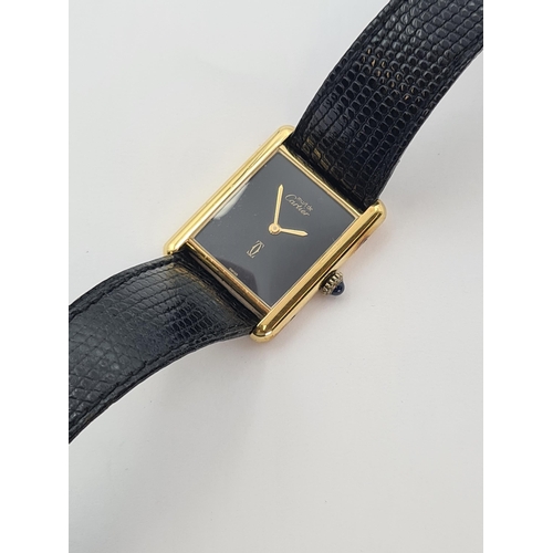 129 - A lady's Must de Cartier manual wind Tank Wristwatch the rectangular black dial with gold hands, sap... 