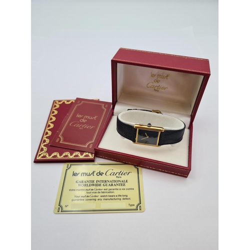 129 - A lady's Must de Cartier manual wind Tank Wristwatch the rectangular black dial with gold hands, sap... 