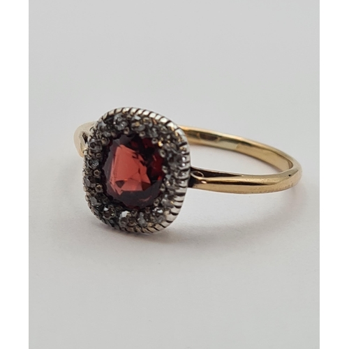 173 - A Garnet and Diamond Cluster Ring set cushion-cut garnet within frame of old-cut diamonds in 18ct go... 