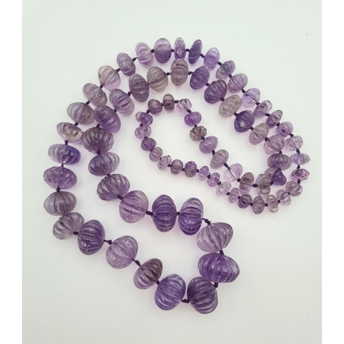 217 - An Indian graduated melon carved Amethyst Bead Necklace, approx 88cms long