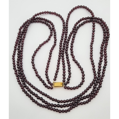 218 - A triple strand Garnet Bead Necklace on gold clasp, approx 76cms long