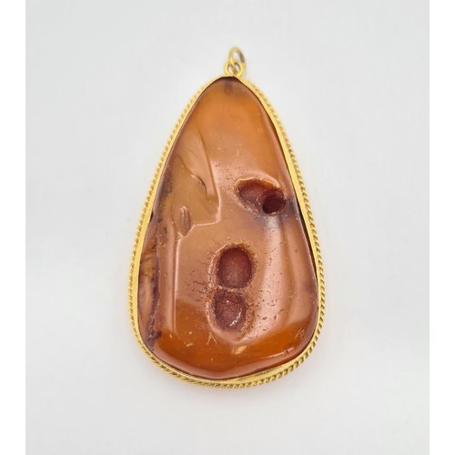 219 - A large Amber Pendant in gold rope twist frame, approx 8.5cms long