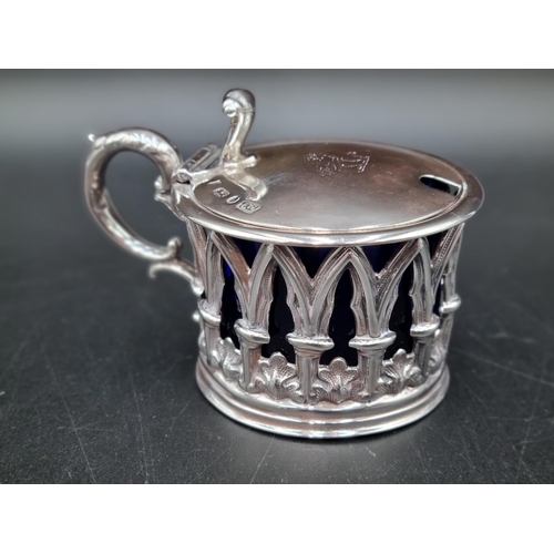 59 - An early Victorian silver Mustard Pot of pierced gothic form, the hinged lid engraved crest, blue gl... 