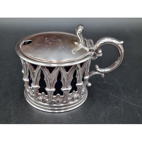 59 - An early Victorian silver Mustard Pot of pierced gothic form, the hinged lid engraved crest, blue gl... 