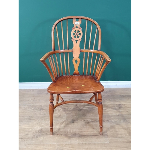 454 - A reproduction ash and elm Windsor Elbow Chair with wheel splat back raised on turned supports and c... 