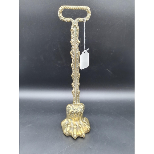 53 - A 19th century brass Door Stop in the form of a lion's paw foot with leafage stem and handle surmoun... 