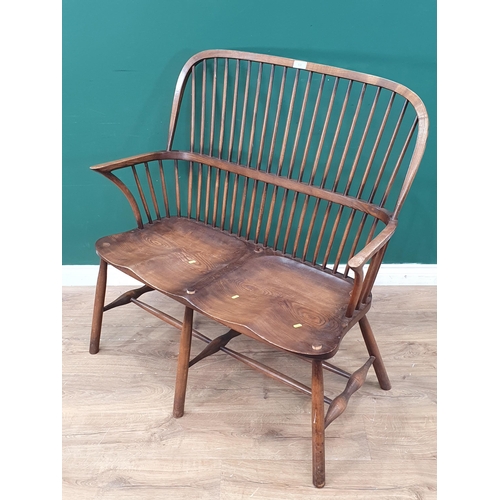 538 - A 'Stewart Linford' Windsor style stick back two seater Bench/Settee with dished seat, on six suppor... 