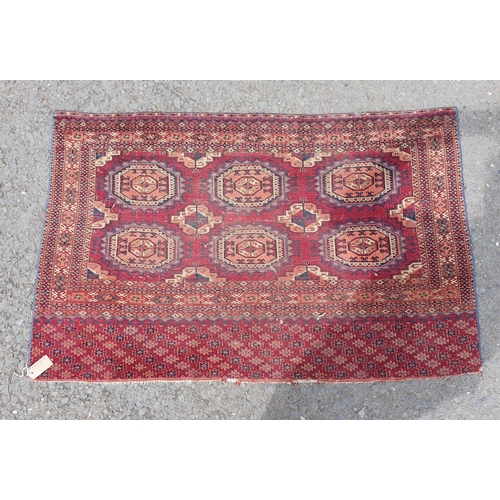 591 - A Persian style Rug on red ground with multiple borders, with six large octagonal geometric motifs, ... 