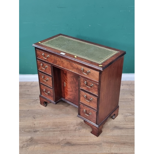 593 - A reproduction mahogany Kneehole Desk, the top with green and gilt inset writing surface, above long... 