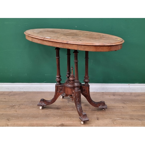 595 - A walnut veneered Loo Table, the oval top with inlaid decoration, raised on four turned columns on c... 