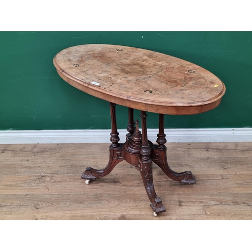 595 - A walnut veneered Loo Table, the oval top with inlaid decoration, raised on four turned columns on c... 