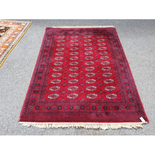 827 - A red ground Rug with multiple floral borders with multiple cross and oval motifs, 7ft 8in L x 5ft 7... 