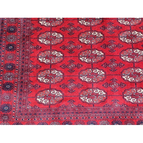 827 - A red ground Rug with multiple floral borders with multiple cross and oval motifs, 7ft 8in L x 5ft 7... 