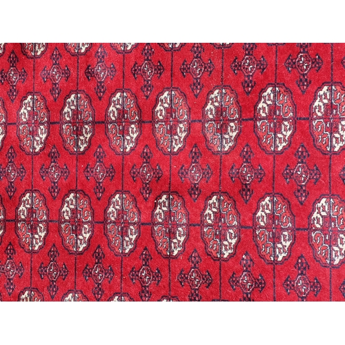 827 - A red ground Rug with multiple floral borders with multiple cross and oval motifs, 7ft 8in L x 5ft 7... 